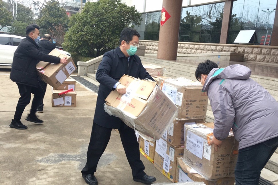 Staff from Asia Symbol help to move boxes of masks donated by the company.
